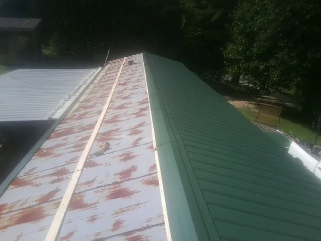 Old rusted panels beside newly installed green metal roofing — Wind Damage Roof Repair by Roofing Brothers in Allenspark