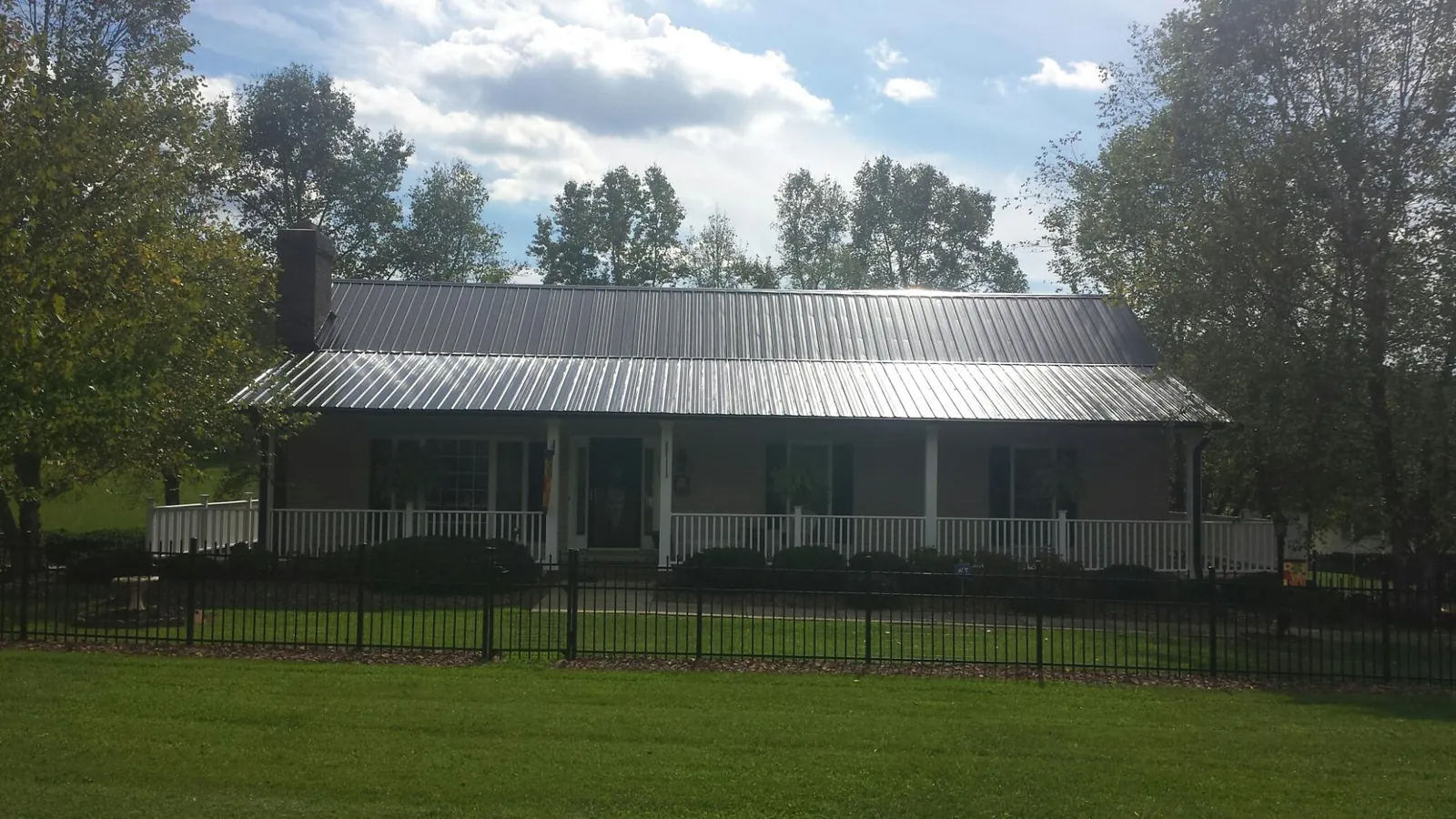 Gray metal roof on a brick ranch with a full width front porch — Gutter Guard Installation work by our crew in Allenspark