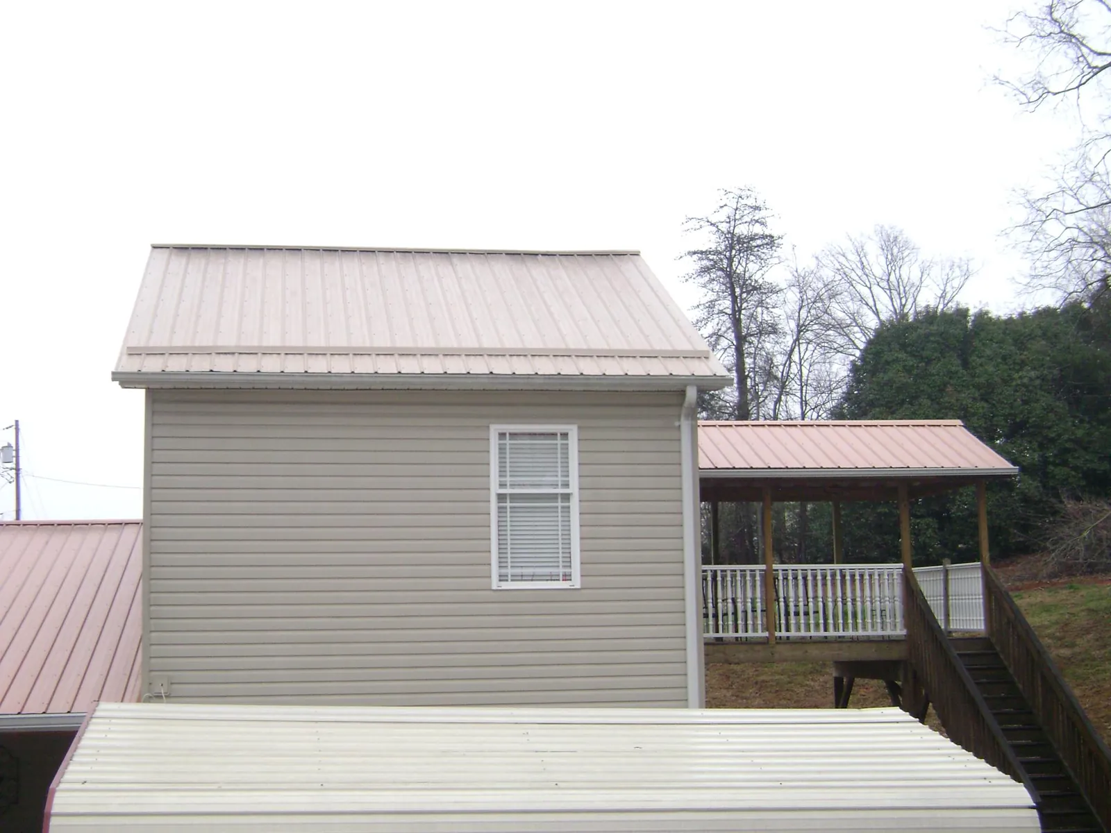 Tan metal roofs on a two story addition and attached porch, from a Roof Replacement job in Allenspark