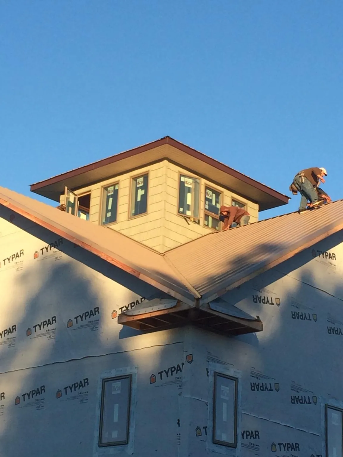 Roofers working around a rooftop cupola on a new metal roof at sunset — Roof Waterproofing in Allenspark by Roofing Brothers